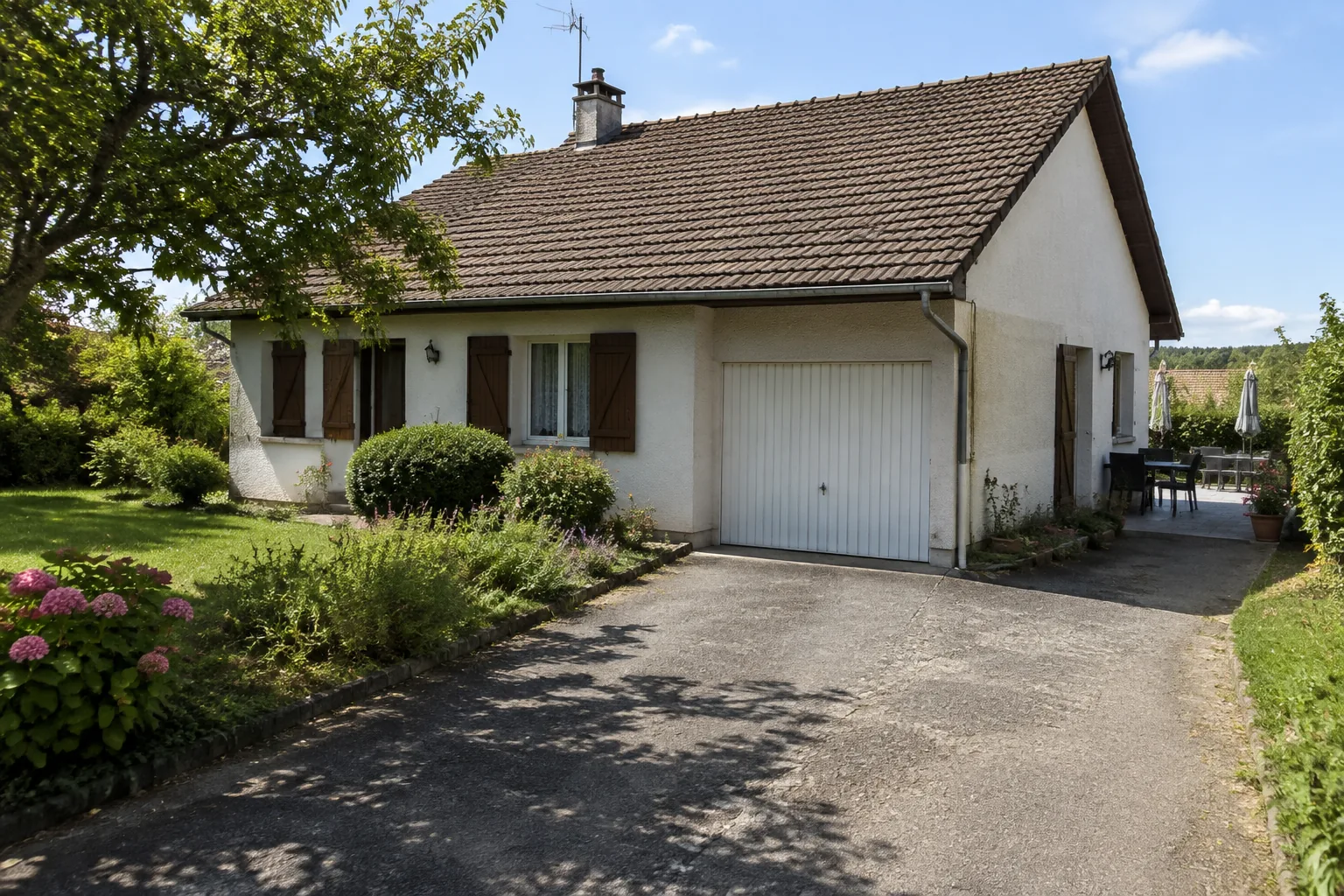 Pavillon vu du haut de l'allée, garage accolé et jardin sur le côté